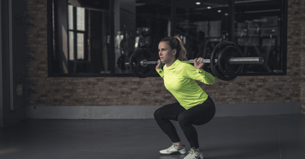 Woman doing weighted squats in a gym.