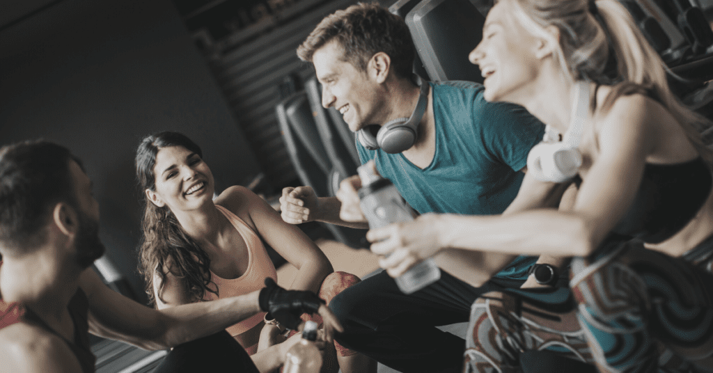 Four people laughing and talking in a gym.