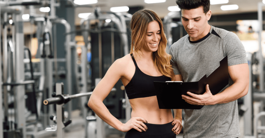 A personal trainer showing a workout plan to their student in a gym.